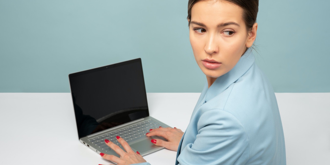 A photograph of a woman nervously working in front of a laptop.
